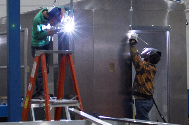 Two workers welding separate objects.
